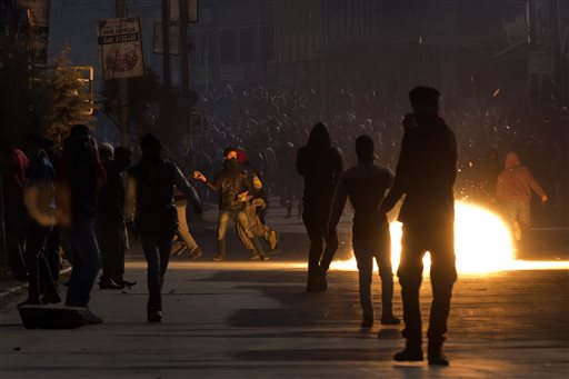 Kashmiri Muslim protesters watch as a tear gas shell fired by Indian policemen explodes near them during a protest in Srinagar, Indian-controlled Kashmir, Friday, Feb. 5, 2016. Government forces fired tear gas to quell protest by hundreds of rock-throwing Kashmiris shortly after Friday prayers in Indian-controlled Kashmir, while displaying Pakistani flags and chanting pro-independence slogans in the regions main city, police said. Pakistanis observe Feb. 5 every year as "Kashmir Day" by holding rallies and arranging seminars on the issue of Kashmir, which is divided between Pakistan and India. (AP Photo/Dar Yasin)